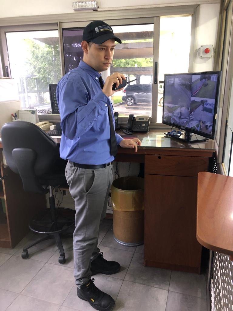 Vigilador de Proyección Seguridad con equipo de radio en un puesto de control